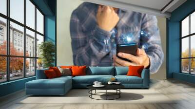 Man holding smartphone with holographic digital security icons, representing online safety, data protection, and cybersecurity concepts. Wall mural