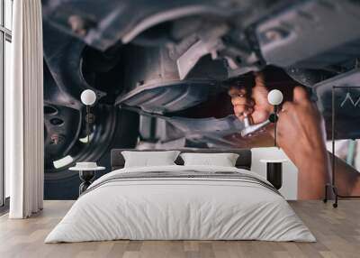 Mid adult mechanic repairing undercarriage of a car in auto repair shop. Wall mural