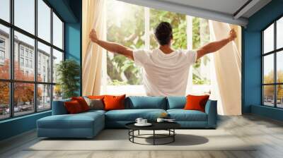 Back view, man and open curtain at window to good morning, sunrise and sunshine to relax in room at home. Guy, wake up and opening bedroom drapes in apartment for sunlight, fresh air or start new day Wall mural