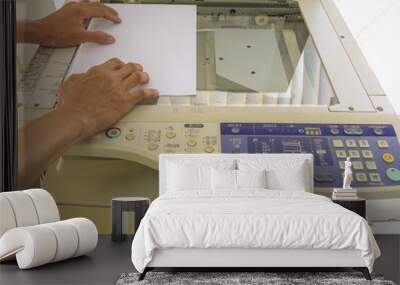 The hands of a young man is placing a piece of paper on a flatbed scanner in preparation for copying it Wall mural