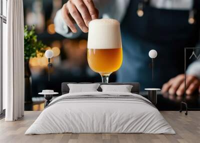 A bartender serving a draft beer, the foam settling perfectly on top of the glass. Wall mural