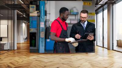 The mechanic discuss with his chief during car damage inspection at the garage  Wall mural