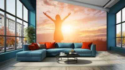 Silhouette of woman praying over beautiful sky background Wall mural