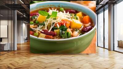 A bowl of vegetable soup with cheese and basil garnish. Wall mural