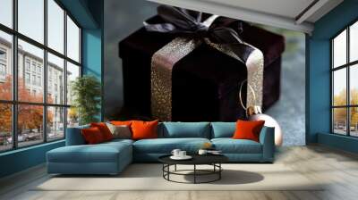 A luxurious black gift box adorned with a ribbon, accompanied by a decorative ornament. Wall mural