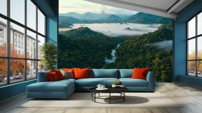 A breathtaking aerial view of lush green mountains enveloped in mist, with a serene river winding through the dense forest landscape. Wall mural