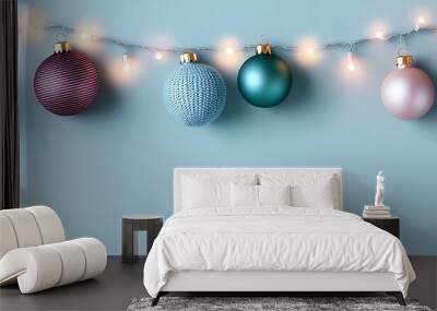 Colorful Christmas ornaments strung with lights against a pale blue background, creating a festive and cheerful holiday atmosphere. Wall mural