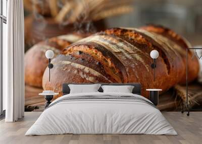 Artisan bread loaf on wooden surface with wheat ears in soft lighting. Wall mural