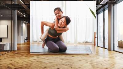 Asian young mother teaching her daughter to yoga pose and exercise together on yoga mat Wall mural