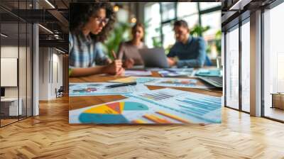 Close-up of a team engaging in a heated market strategy discussion, with financial papers and laptops scattered around Wall mural