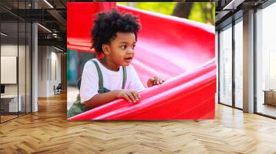 Cute African American little kid boy having fun while playing on the playground in the daytime in summer. Outdoor activity. Playing make believe concept. Outside education Wall mural