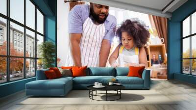 Happy African American father and daughter having fun while preparing cookie dough at home. happy family time. Wall mural