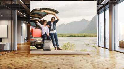 Asian couple Man with vintage camerra and woman sitting on back of car  travel to mountain and lake in holiday with car road trip Wall mural