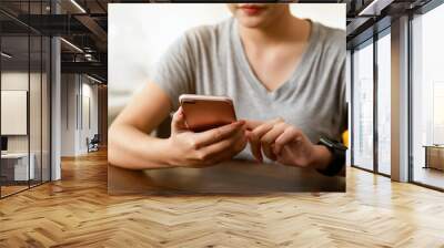 Woman holding a smartphone and using social media on internet. Wall mural