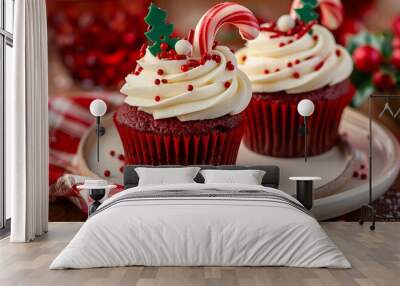 Two cupcakes with holly and red berries, candy cane decorations on top of the frosting Wall mural