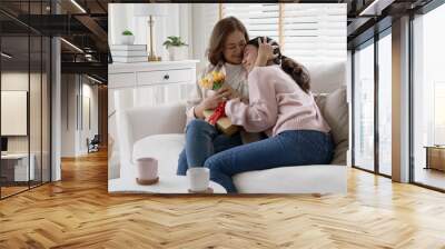 Attractive beautiful asian middle age mum sit with grown up daughter give gift box and flower in family moment celebrate mother day. Overjoy bonding cheerful kid embrace relationship with retired mom. Wall mural