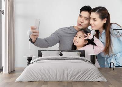 Candid of young attractive happy asian family using smartphone selfie together or video call. Social media community in asian family using 5G digital technology conference to connected people concept. Wall mural