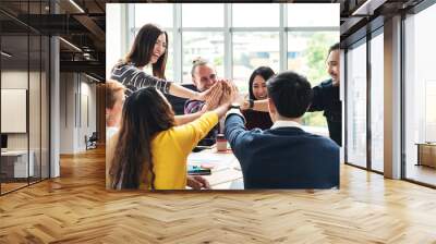 group of young multiethnic diverse people gesture hand high five, laughing and smiling together in brainstorm meeting at office. Casual business with startup teamwork community celebration concept. Wall mural