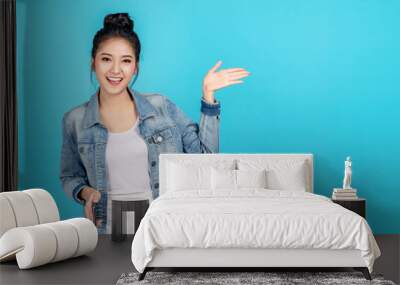 Happy asian woman feeling happiness and standing hold smartphone other hand open on blue background. Cute asia girl smiling wearing casual jeans shirt and connect internet shopping online and present Wall mural