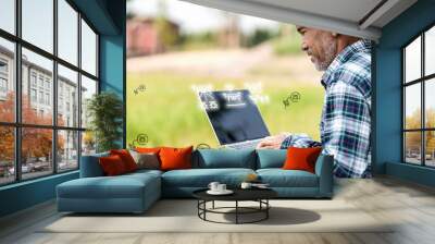 Old asian farmer is choosing program pest control with drone by computer laptop. Asia man is monitoring pest with digital technology in smart farm. Internet of thing, agriculture and smart farming. Wall mural