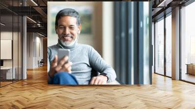 Portrait of attractive mature asian man retired with stylish short beard using smartphone sitting or listening music in urban lifestyle coffee shop. Old man using social network internet technology. Wall mural