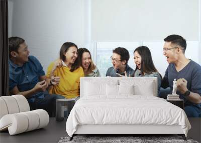 Young Attractive asian group of friends talking and laughing with happy in gathering meeting sitting at home feeling cheerful and enjoy game in leisure time together. People in blue or yellow wearing. Wall mural