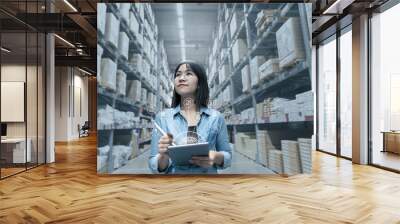 Young attractive asian manager woman looking, picking, replemishment, receiving inventory at store warehouse in warehouse management system concept. Smart ERP with iot for inventory management. Wall mural