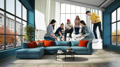 Young creative diverse group meeting and looking at project plan lay out on floor discuss or brainstorm business strategy with post note. Workshop for startup team in modern office. Happy workplace. Wall mural