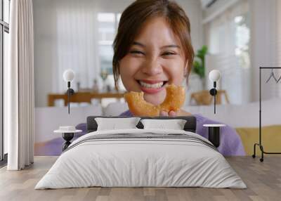 Young vlogger asia people influencer girl take photo eat bite smiley donut funny face post review on instagram tiktok reel app. Sweet tooth food sugar lover enjoy fun show viral video camera at home. Wall mural