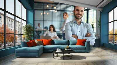 A portrait of a cheerful businessman standing in a conference room with his arms crossed. Wall mural