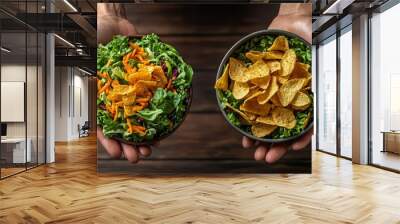 Top-down view of healthy salad versus a bowl of chips in hands, representing the decision between balanced eating and junk food Wall mural