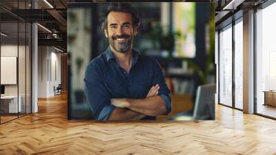 A handsome, happy, courageous, successful man with a wide smile on his face stands in front of a desk with a laptop and a computer monitor Wall mural