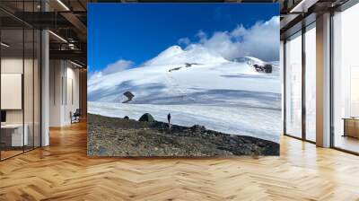 A lone climber stands next to a tent in an assault camp near Mount Kazbek, from the Russian side. Wall mural