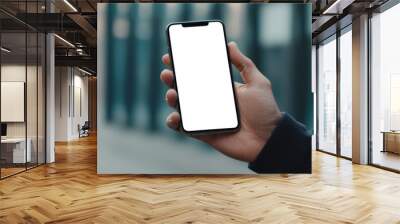 A man is holding a phone with a white screen in his hand. A mockup of a modern phone in a man's hand on the street. Mobile app advertising Wall mural