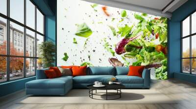 A salad with a lot of various greens flies into the air. Lettuce leaves, arugula, dill, parsley, spinach, basil and cherry tomatoes are mixed in the air on a white background Wall mural