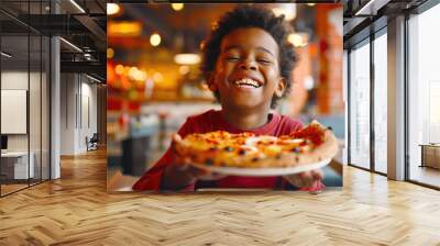 Italian cuisine. A little black boy is smiling and laughing, holding a plate of delicious mouth-watering hot pizza in his hands. The concept of happiness and enjoyment Wall mural