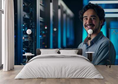 The young specialist is in the data center. A happy man smiles in front of a row of computer servers Wall mural