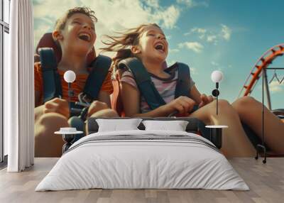 Two children are riding a roller coaster and laughing in fear. Brother and sister have fun at the amusement park on a sunny summer day Wall mural