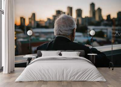 A senior executive in a suit stands at the edge of a city skyline, looking contemplative as they prepare to leave their office. Thinking, Transition, Success, Ambition, Opportunity, Challenge Wall mural