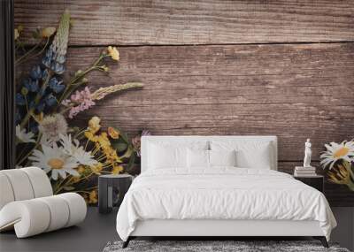 Wild flowers on old grunge wooden background (chamomile lupine dandelions thyme mint bells rape) Wall mural