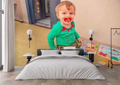 Cheerful baby with a pacifier in his mouth and a 11 months old milestone card with his toys Wall mural