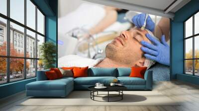 Man receiving cosmetic treatment of face Wall mural