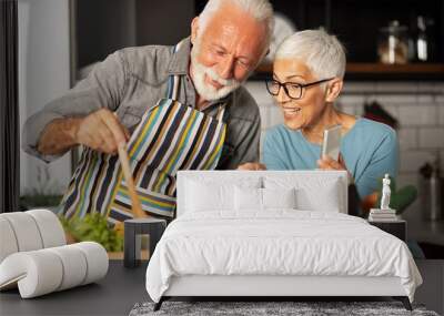 Senior couple shares a video call with their friends how prepare meal Wall mural