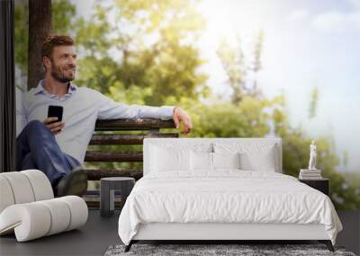 young handsome business man in suit relax on bench in park Wall mural