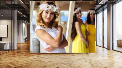 Beautiful Bride and two bridesmaids in yellow similar dresses together in a sea restaurant Wall mural