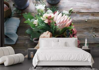 Florist at work: pretty young blond woman making fashion modern bouquet of different flowers Wall mural