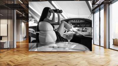 Young beautiful woman in a long silk black dress posing on a yacht. Luxurious life style, summer time Wall mural