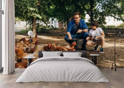 Boy and his dad crunch to feed the chickens. Wall mural