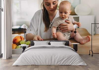 Caring mother is feeding her child. Wall mural