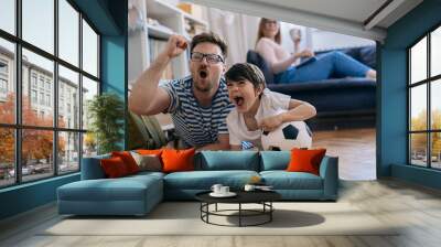 cheerful father and son watching soccer game at home Wall mural